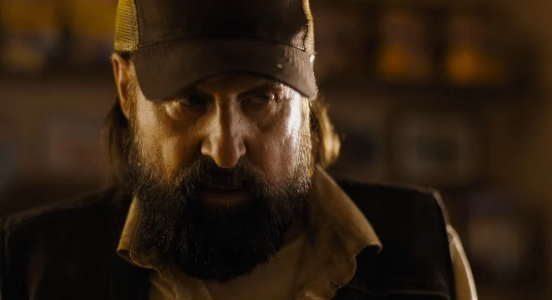 A man in a trucker hat looks at the camera. 