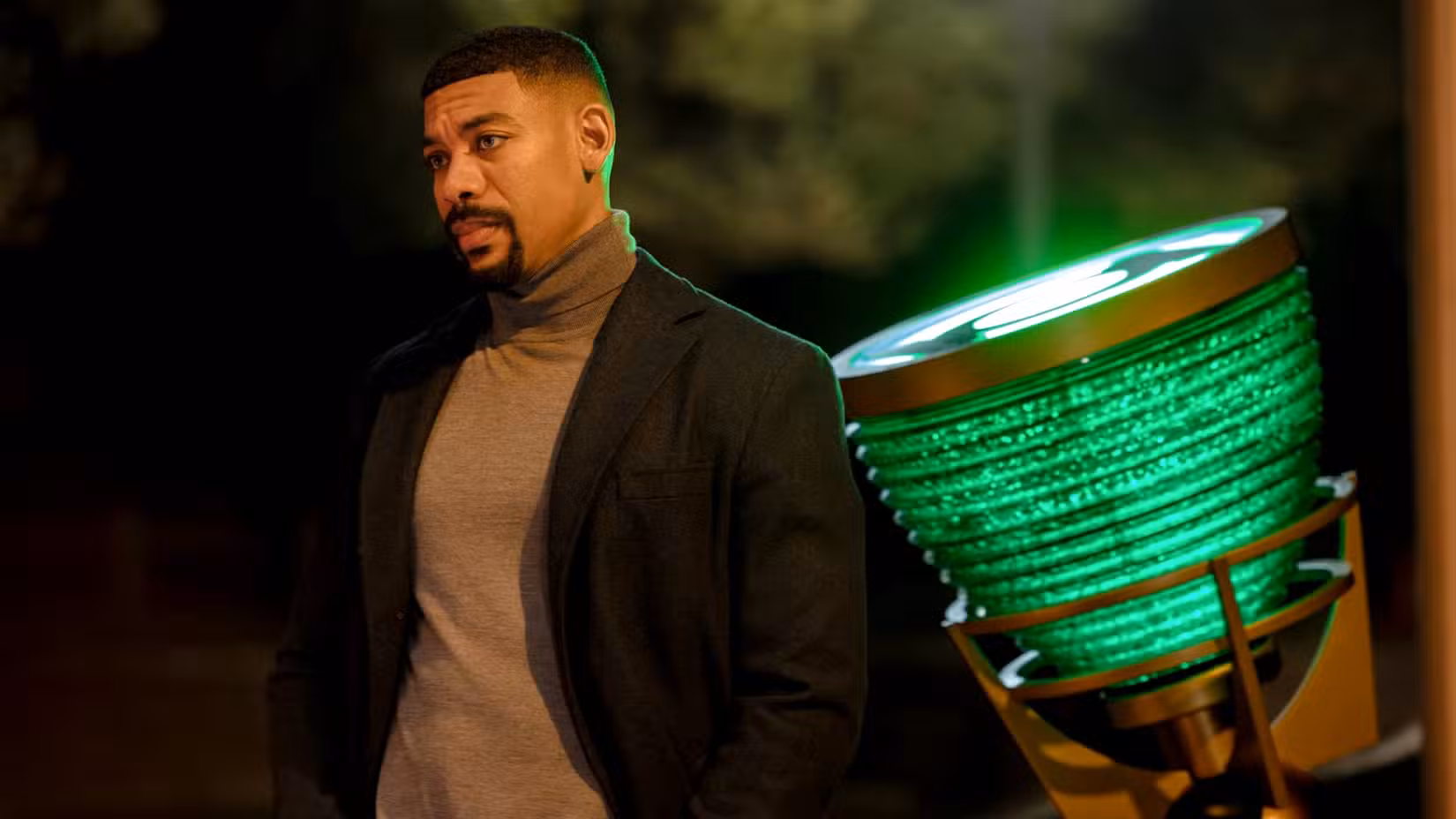 Aaron Pierre as John Stewart looking at someone with the Green Lantern signal behind him