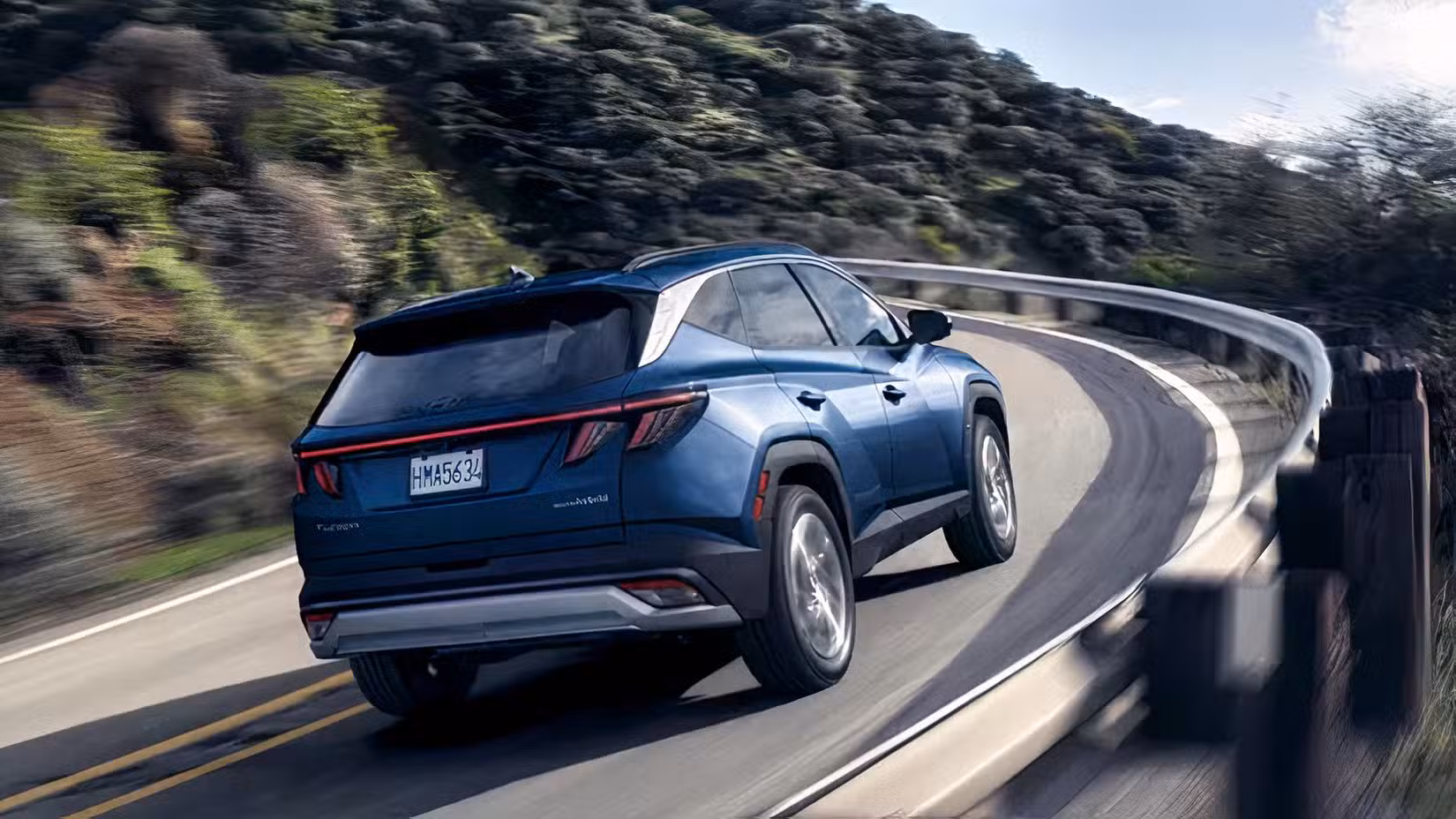 Rear 3/4 shot of 2026 Hyundai Tucson Hybrid driving on road