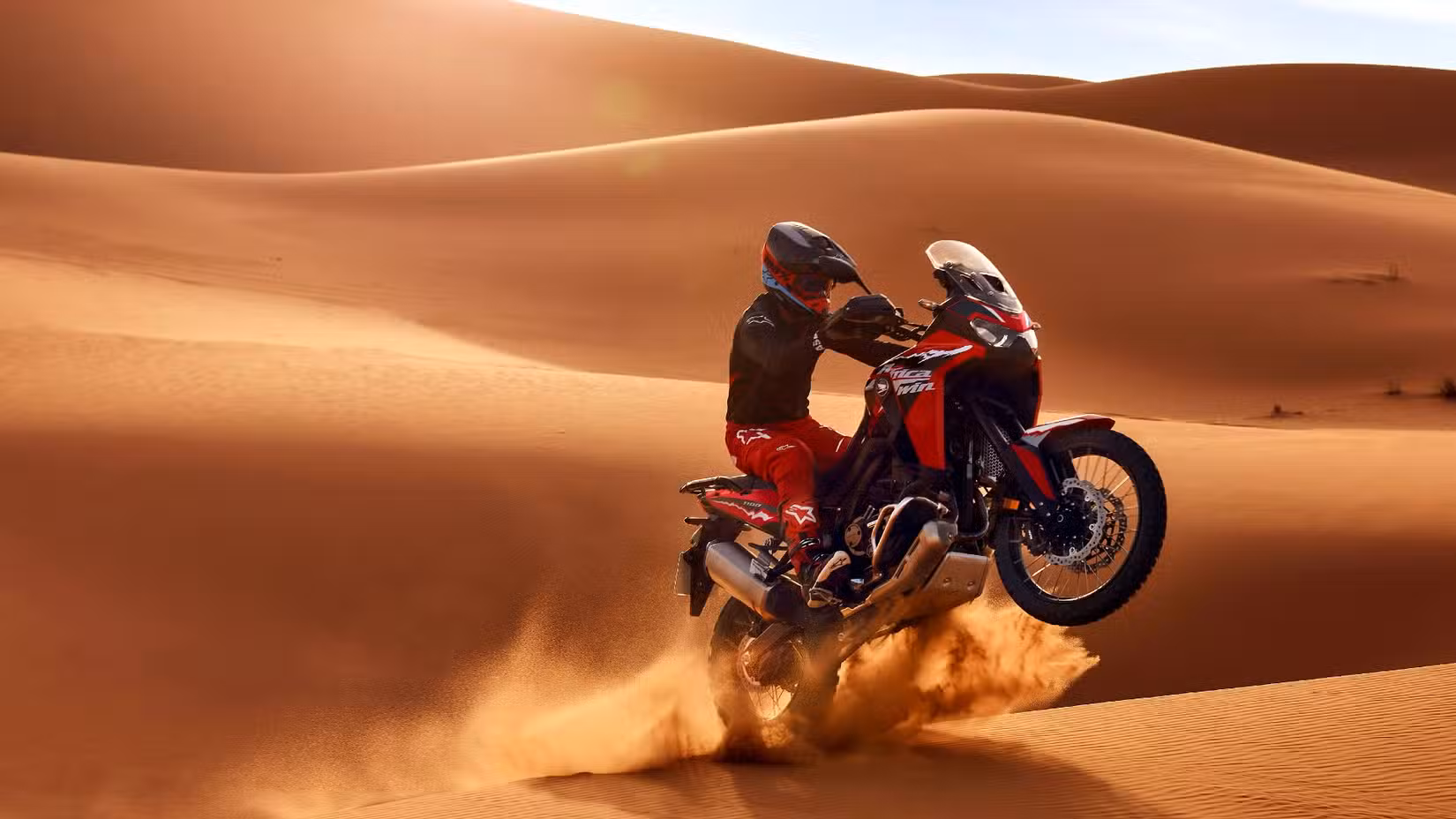 Action shot of the Africa Twin jumping over a dune