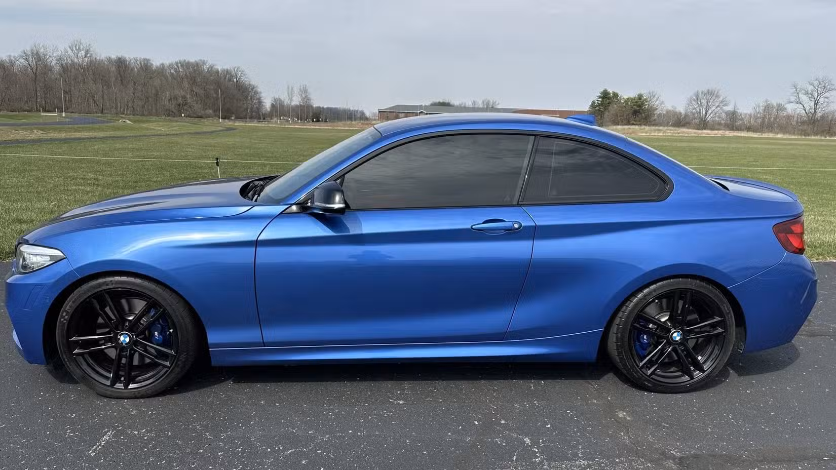 The side profile view of a blue 2021 BMW M240i Coupe.