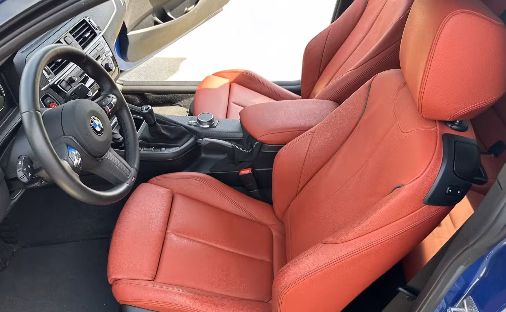 The front seats of a blue 2021 BMW M240i Coupe.