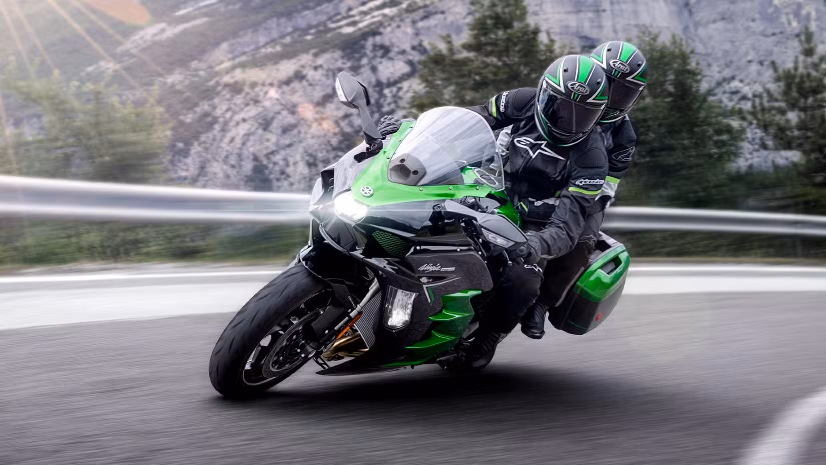 A 2024 Kawasaki Ninja H2 SX cornering fast on a mountain road