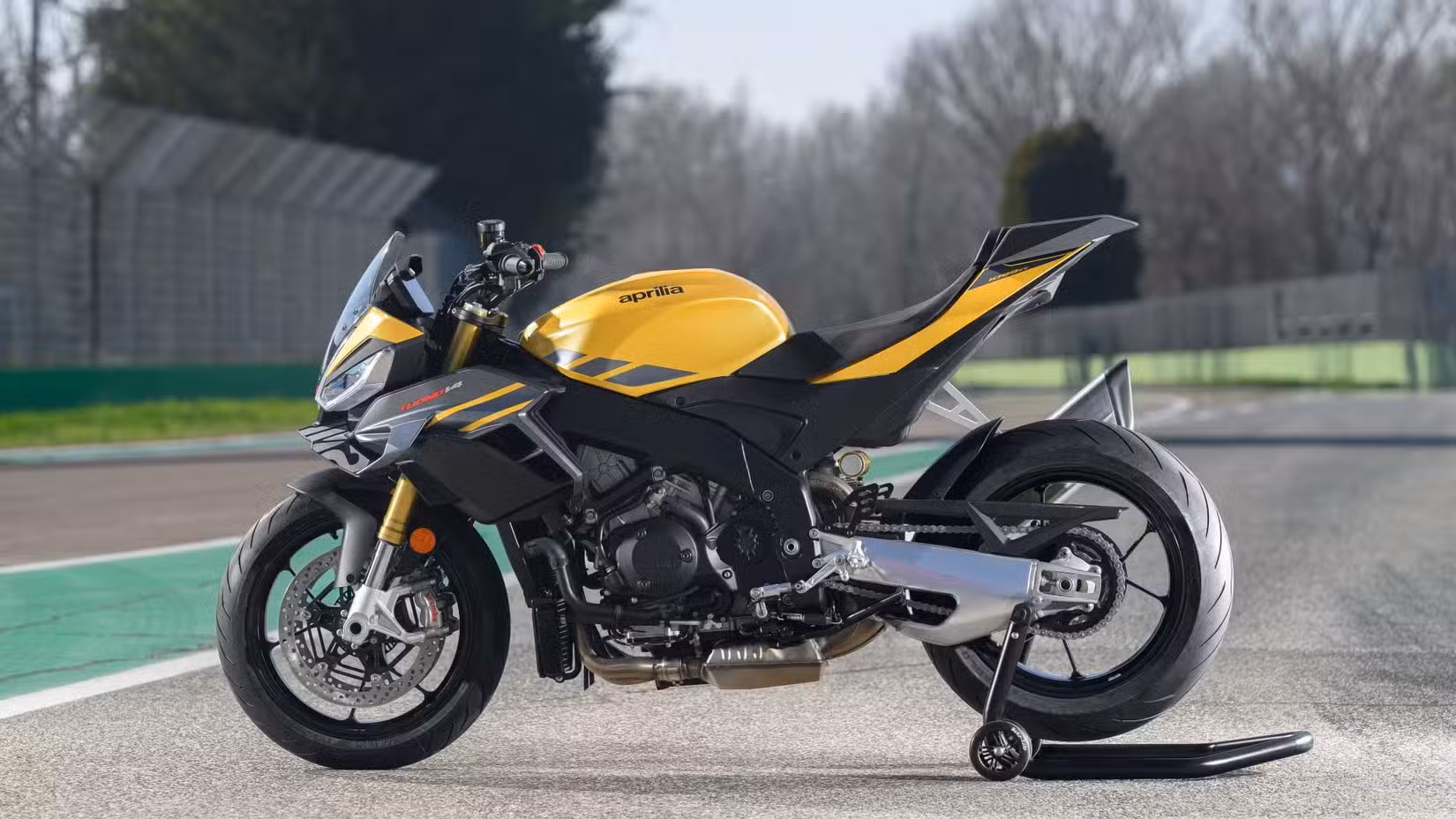 2025 Aprilia Tuono V4 Side Yellow Left on a paddock stand at a racetrack