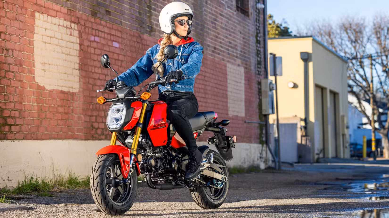 A motorcyclist sitting on a parked Honda Grom