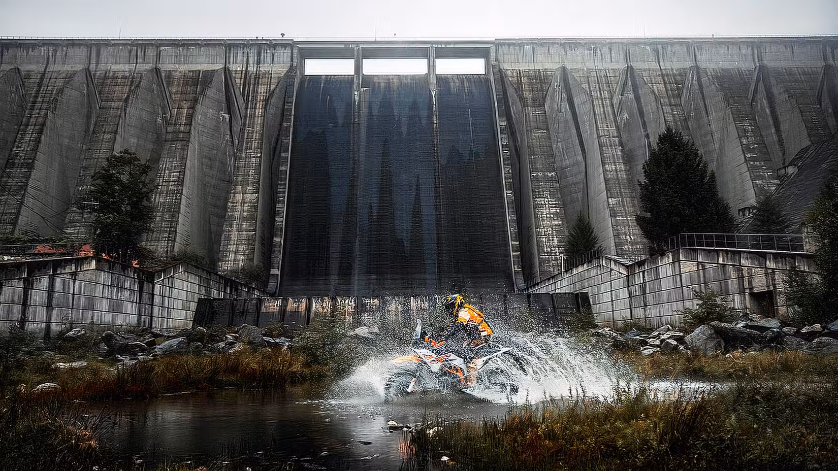 2025 KTM 390 Adventure R splashing through the water in front of a dam