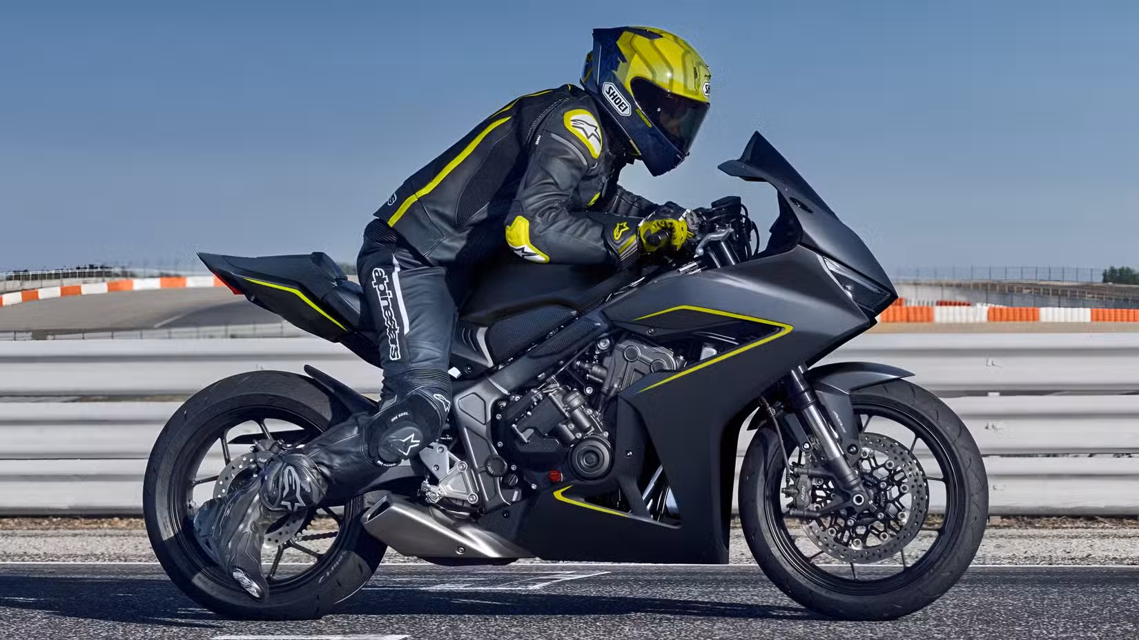 2026 Honda CBR650R in black, side profile view taking off from a racetrack starting line