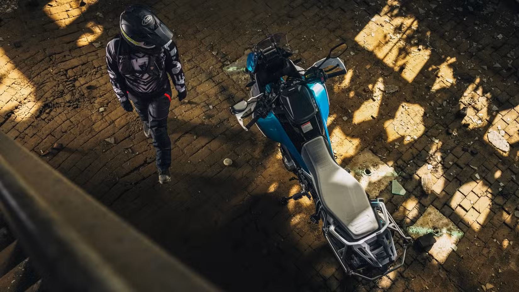 Rider standing beside a parked 2026 CFMoto Ibex 450 ADV top angle shot