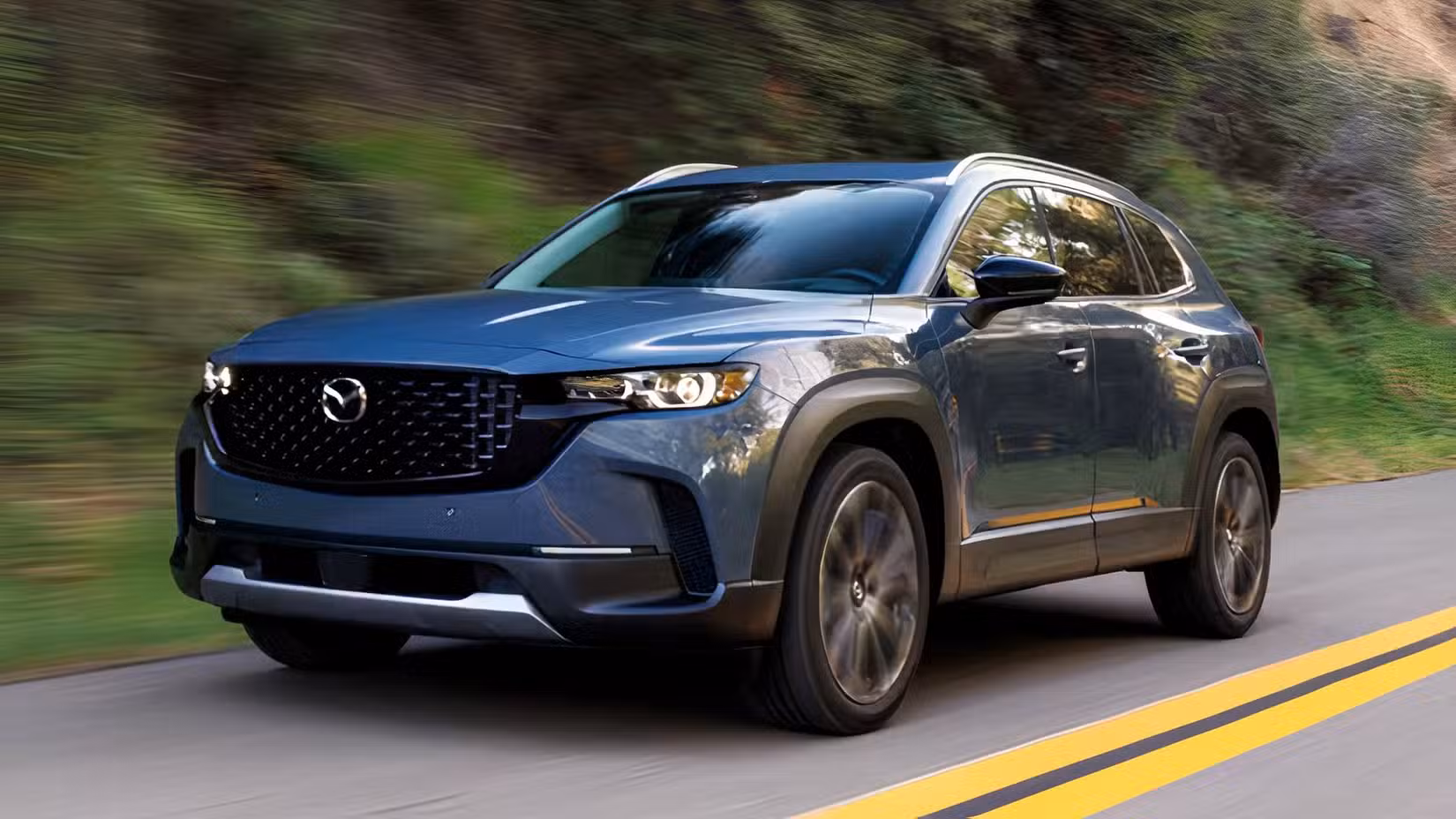Front 3/4 action shot of 2026 Mazda CX-50 driving on road