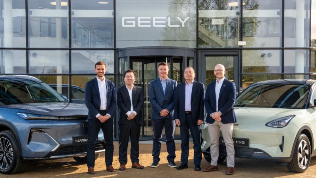 Representatives pose between a Geely Starray EM-i and an EX2 outside a building with Geely signage.
