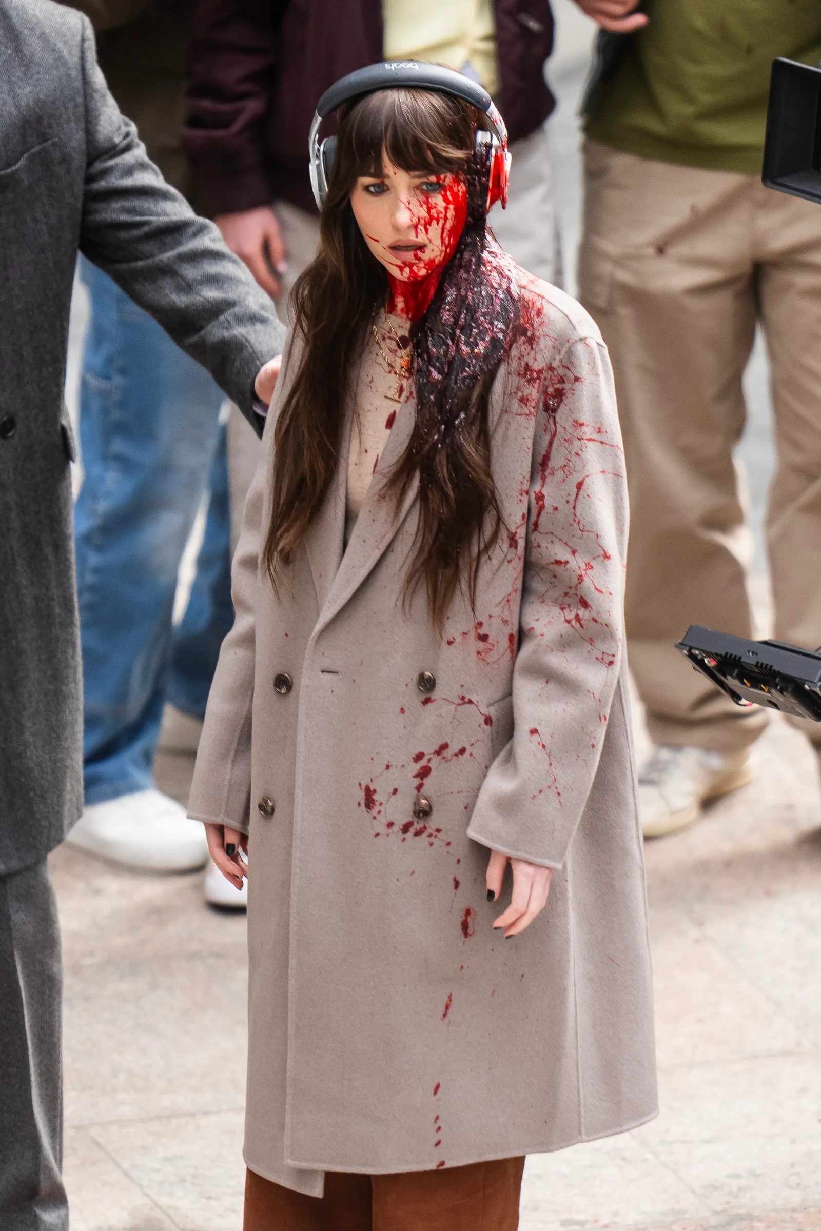 Image may contain Dakota Johnson Clothing Coat Adult Person Electronics Headphones Wedding Face Head and Gun