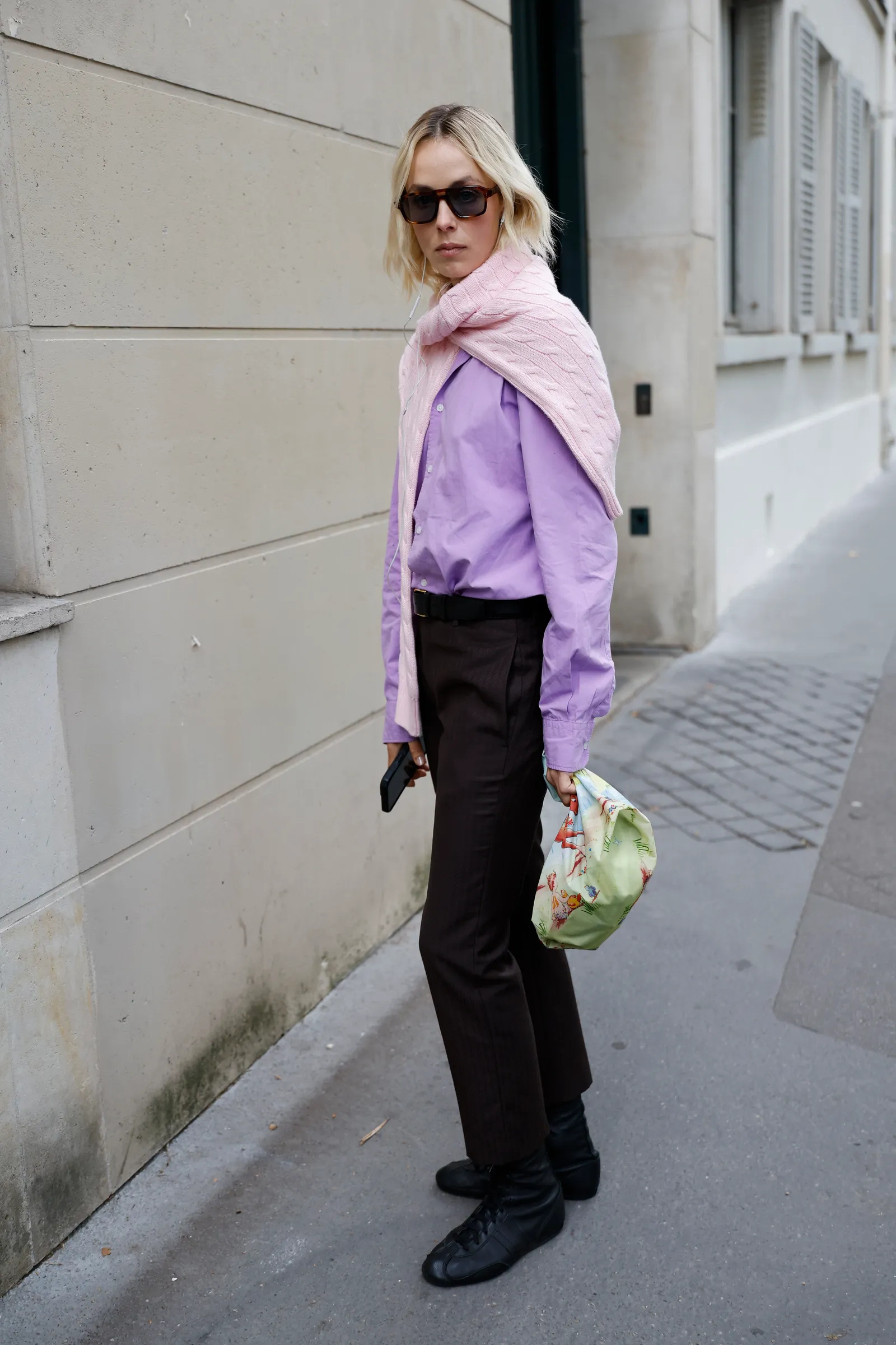 PARIS FRANCE  OCTOBER 01 A guest wears lilac shirt pink sweater on the shoulders brown trousers black leather sneakers...