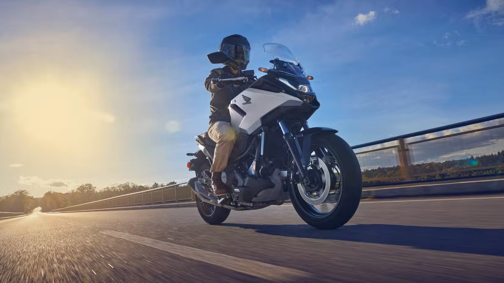 Honda NC750X DCT rolling down a highway cinematic front third quarter view