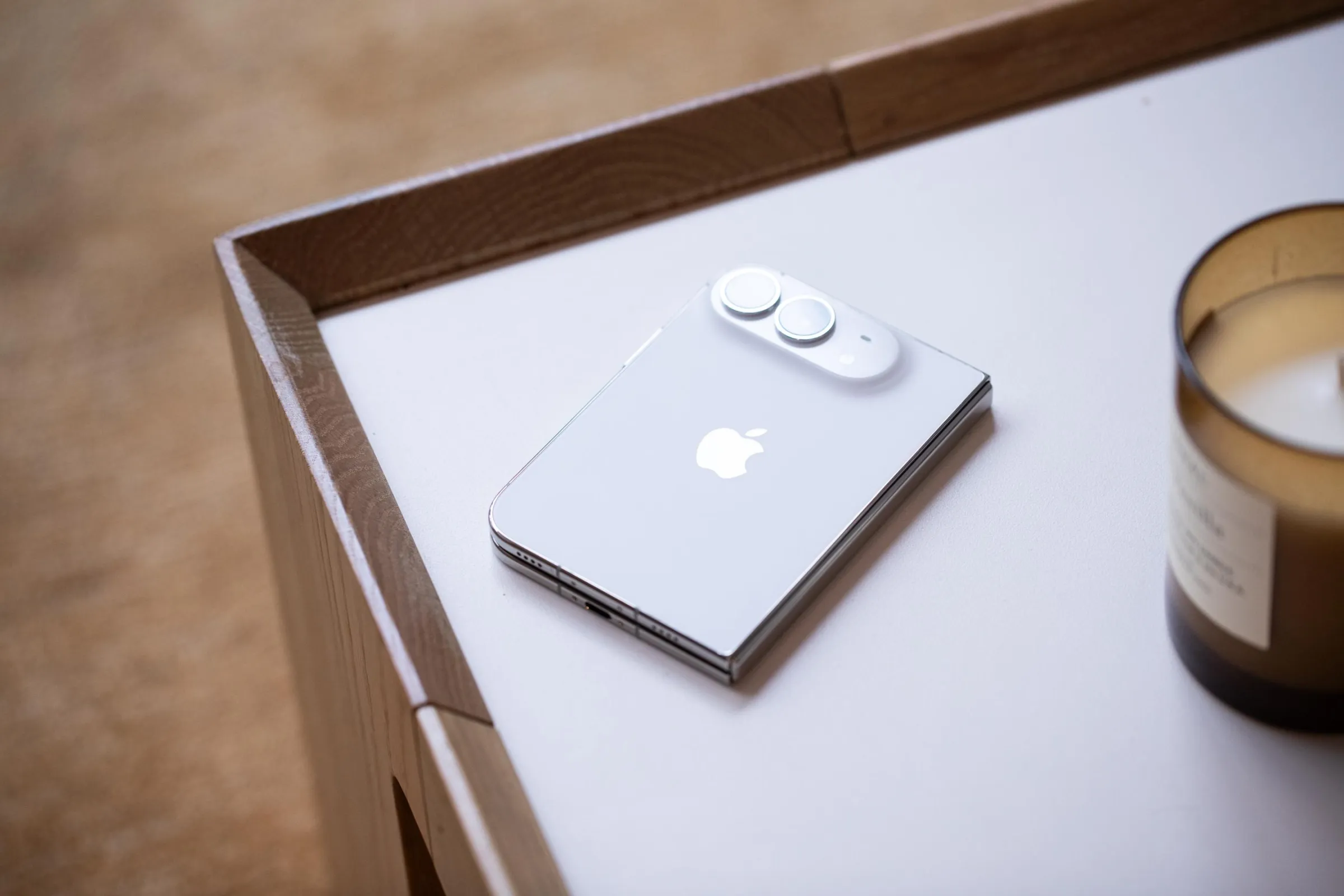 A white iPhone Duo face-down in folded mode on a table.