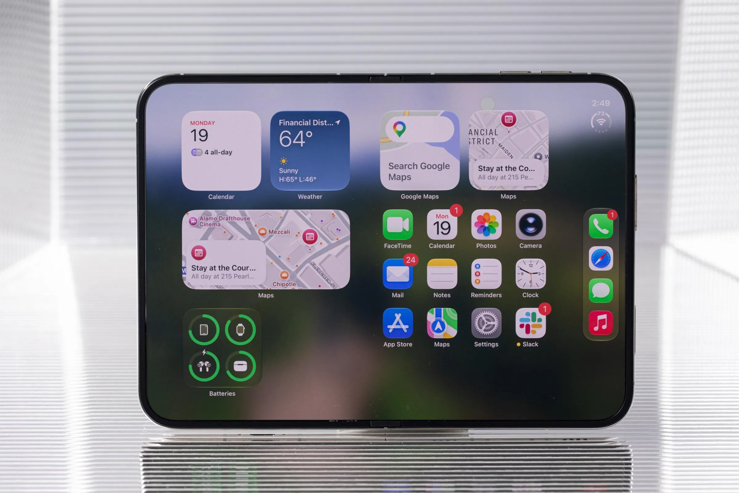 An iPhone Duo opened to the inner screen in landscape orientation. It’s showing the weather, map widgets, and other apps.