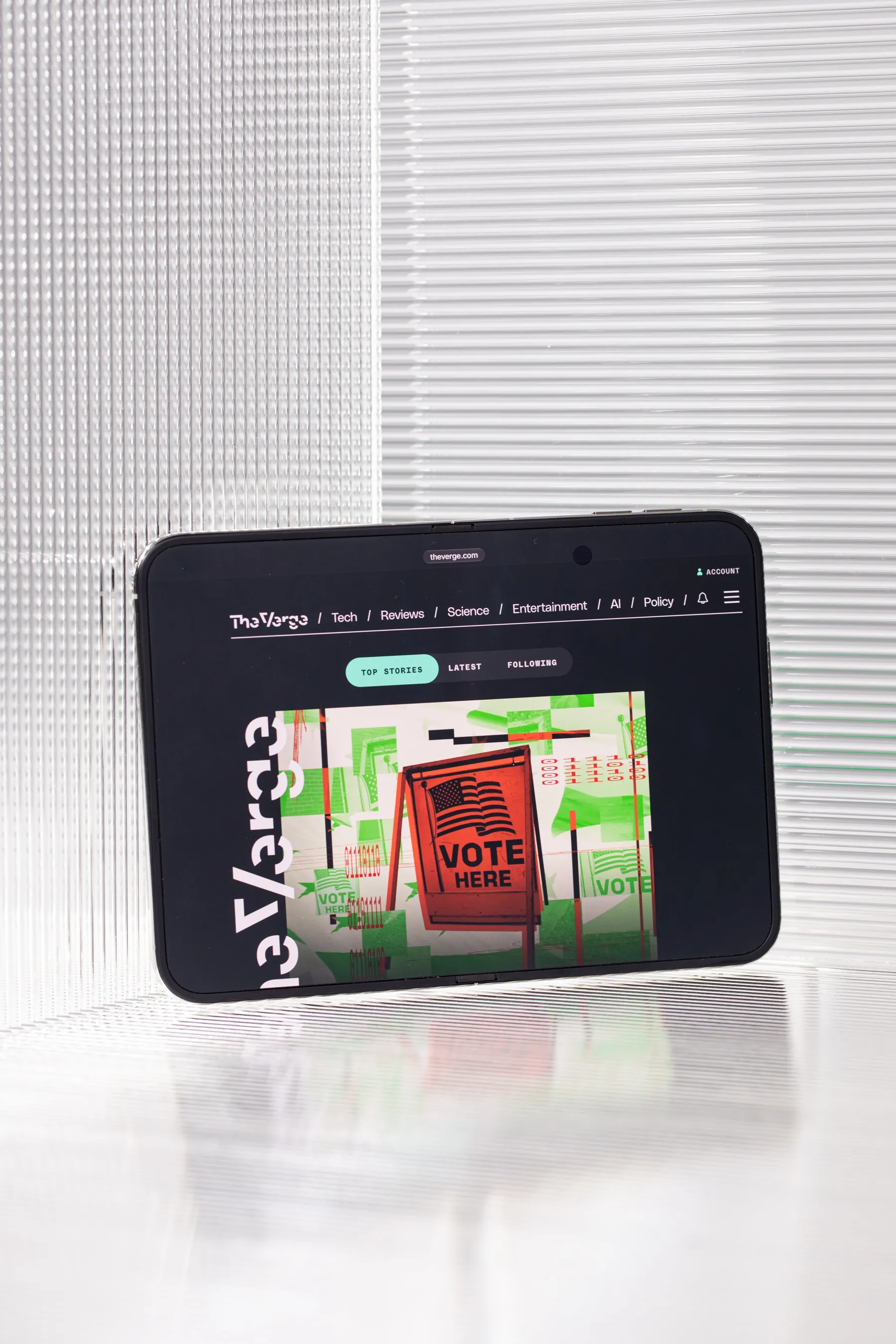The iPhone Duo opened to the matte inner screen in landscape orientation, displaying the homepage of The Verge.