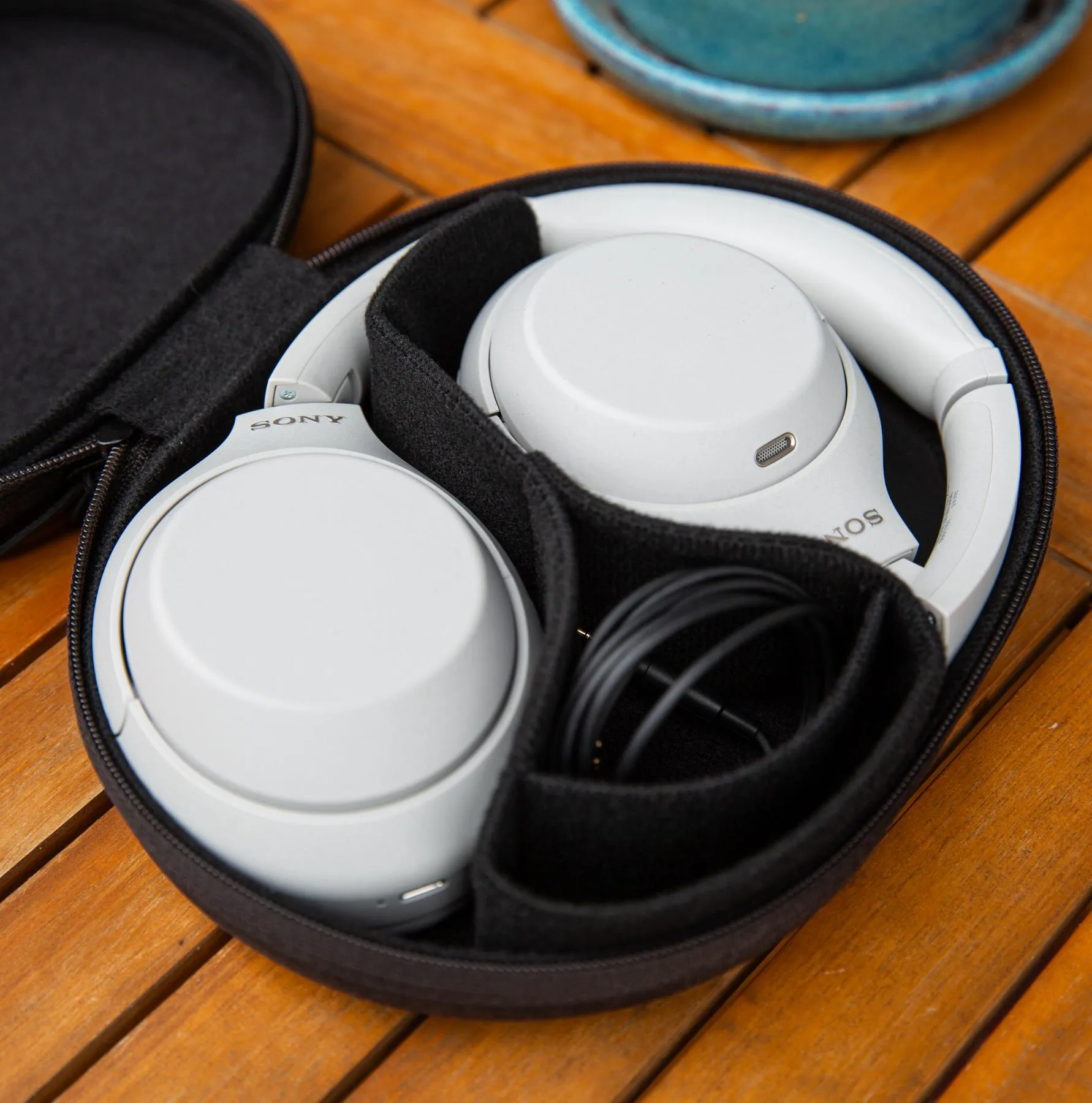 The Sony XM4C in their carrying case on a wooden table.