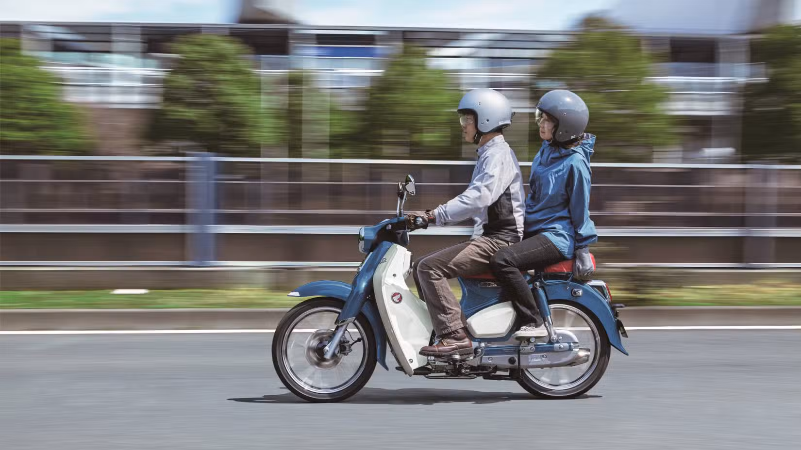 Honda Super Cub side action shot with rider and pillion