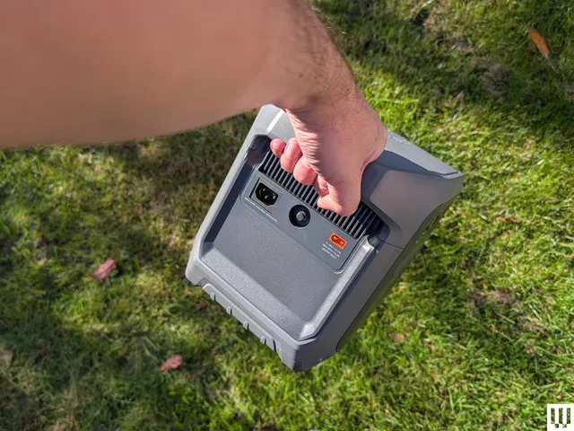 Hand holding a grey square device by the large handle