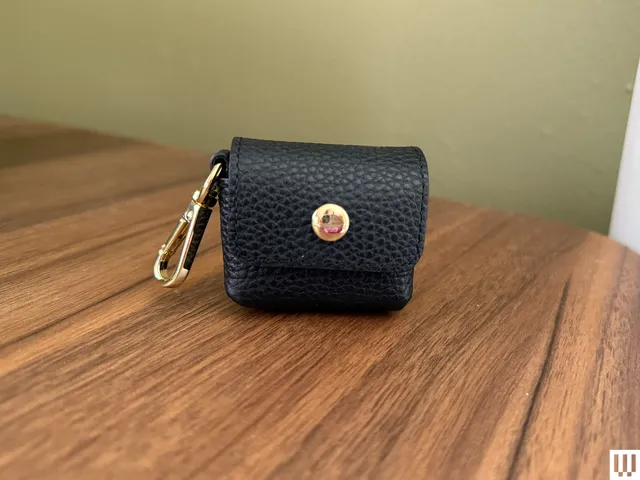 Bandolier Avery AirPods Clip-On Pouch in black and gold sitting on a wooden surface