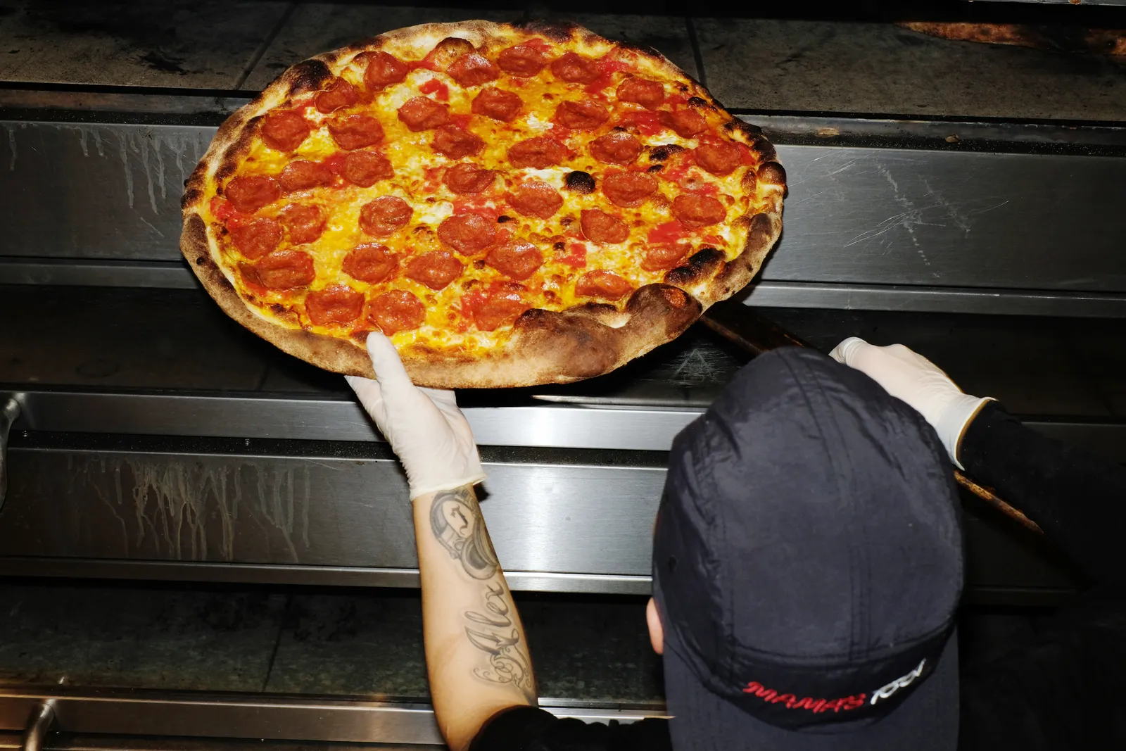 A Mama's Too pizza being pulled from an oven.
