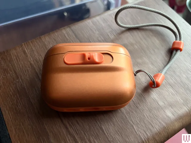 Small orange case with rounded edges and a wrist strap 