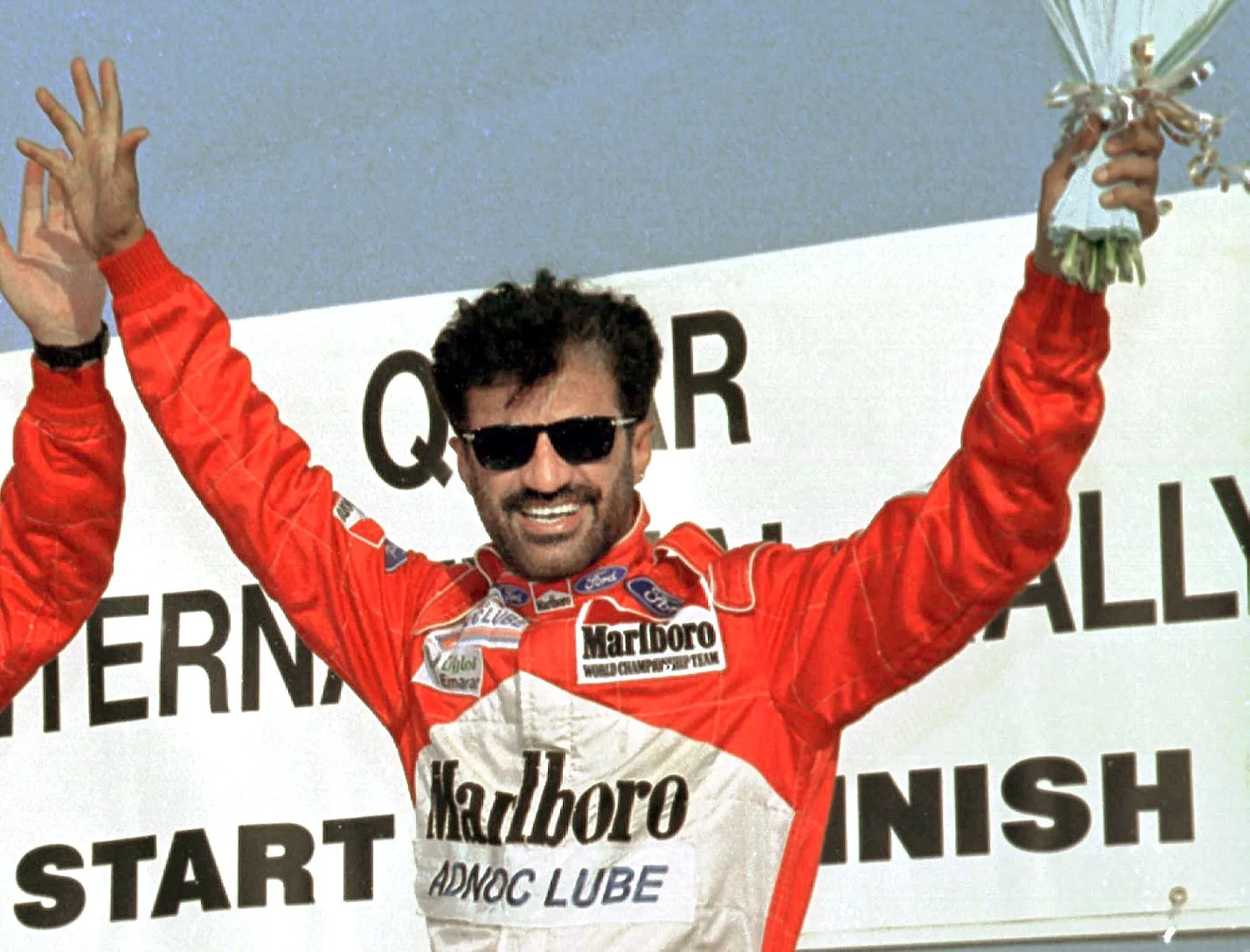 United Arab Emirates rally driver Mohammed Bin Sulayem celebrates his victory at the finish ramp of Qatar International rally 09 October. Ben Sulyem, already the season's champion, took ten minutes off second placed Abdullah al-Qassimi of Sharjah. (Photo by JORGE FERRARI / AFP)