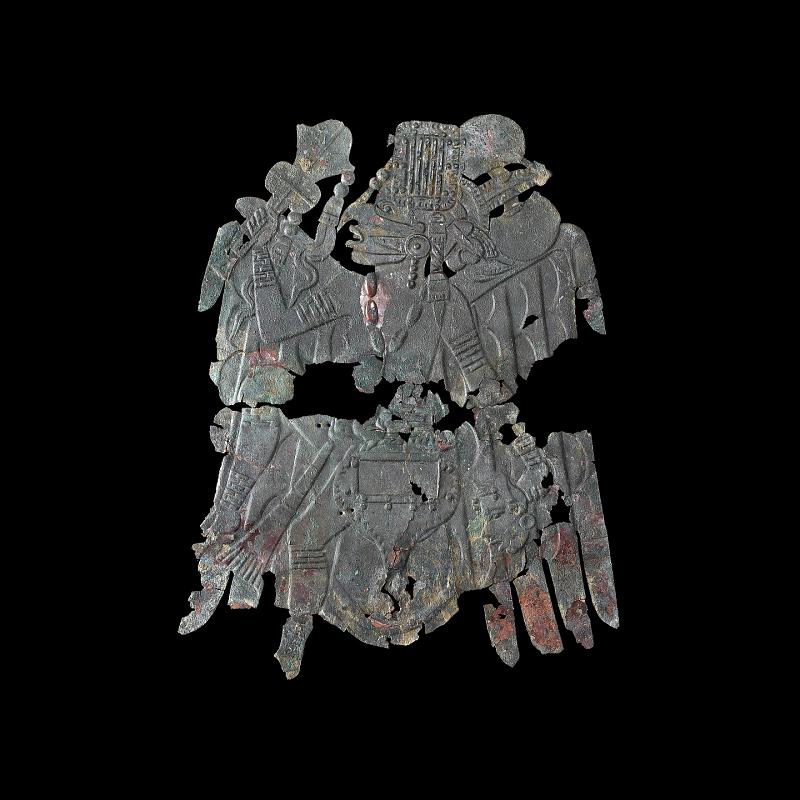 a copper plate in the shape of a human wearing a bird costume against a black background