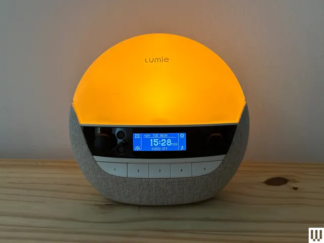 Lumie Bodyclock Luxe 700FM, a circular alarm clock with illuminated top and digital screen with physical buttons below