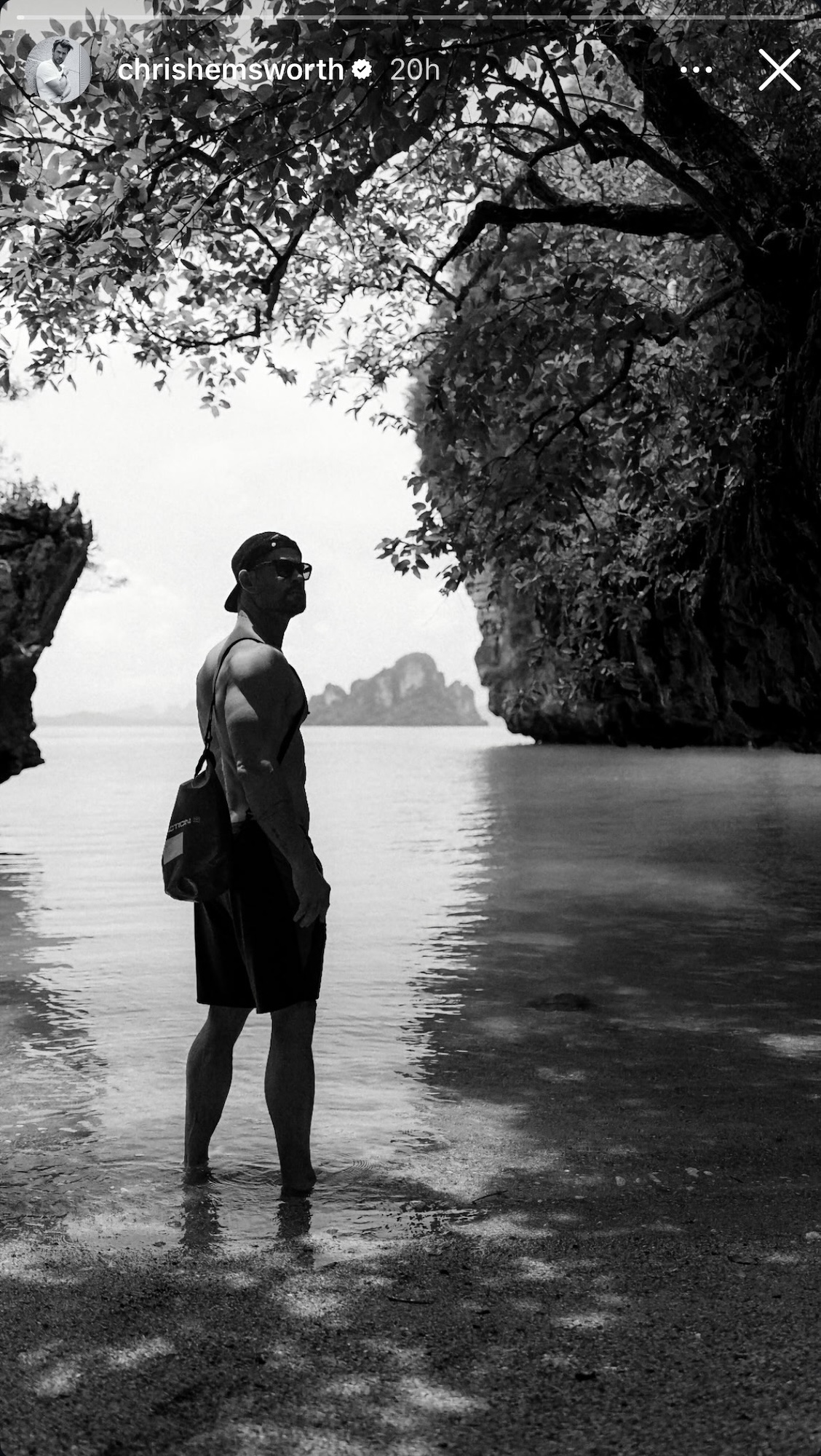 Chris Hemsworth shirtless with his back turned in a black and white photo from IG Story in a tropical location.