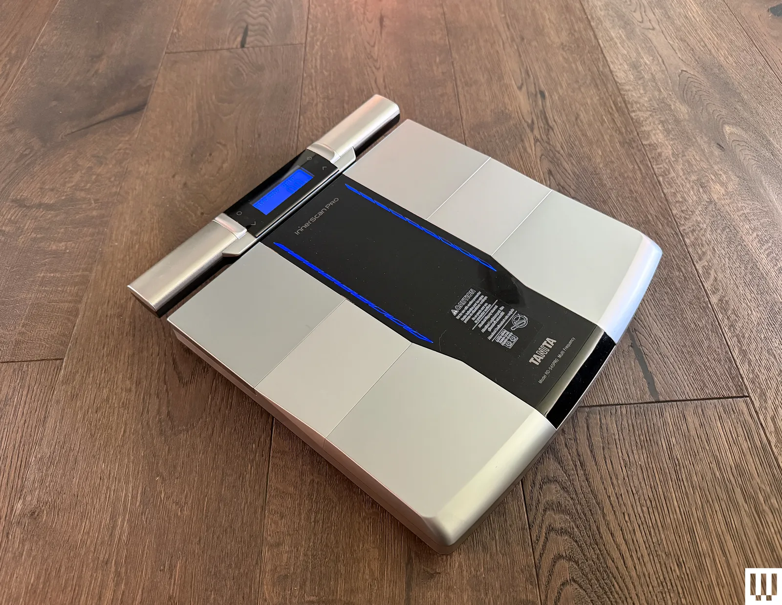 Slim silver scale with digital screen on top of a wooden floor