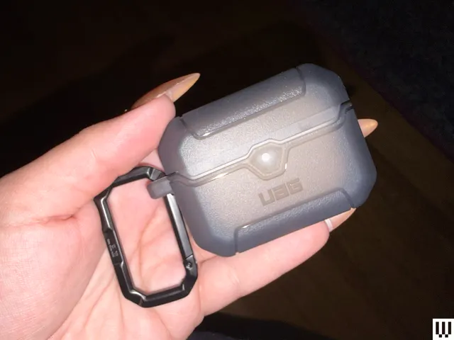 Hand holding a small rectangular case with a keychain attached