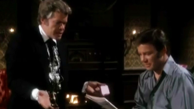 William Shatner's Jeff Cable sits reading a newspaper while Doug McClure's Cash Conover watches in Barbary Coast