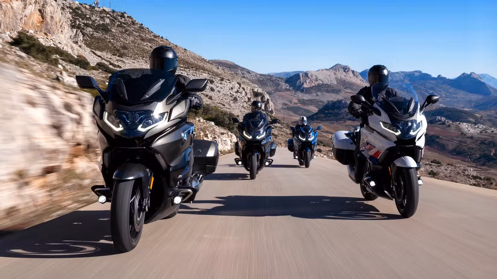 Action group shot of BMW K 1600 series motorcycles riding on a mountain road