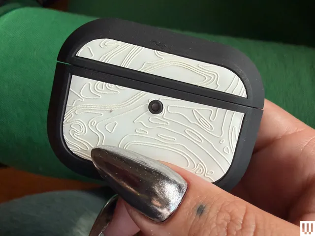 Person's hand pinching a small white case with rounded edges and black trim