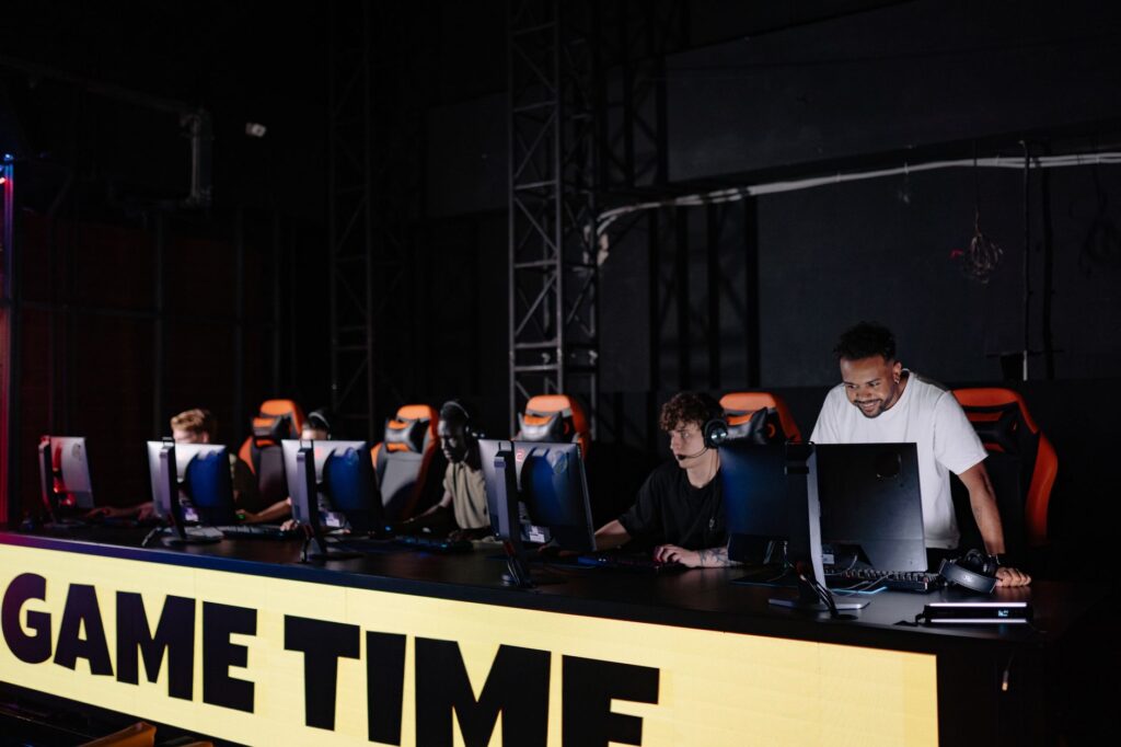 Esports players at computers on a dark tournament stage behind a GAME TIME banner