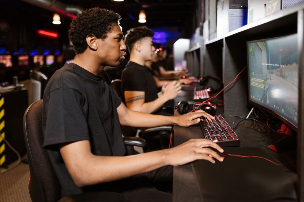 Row of players wearing headsets compete at computer stations in a dimly lit gaming arena
