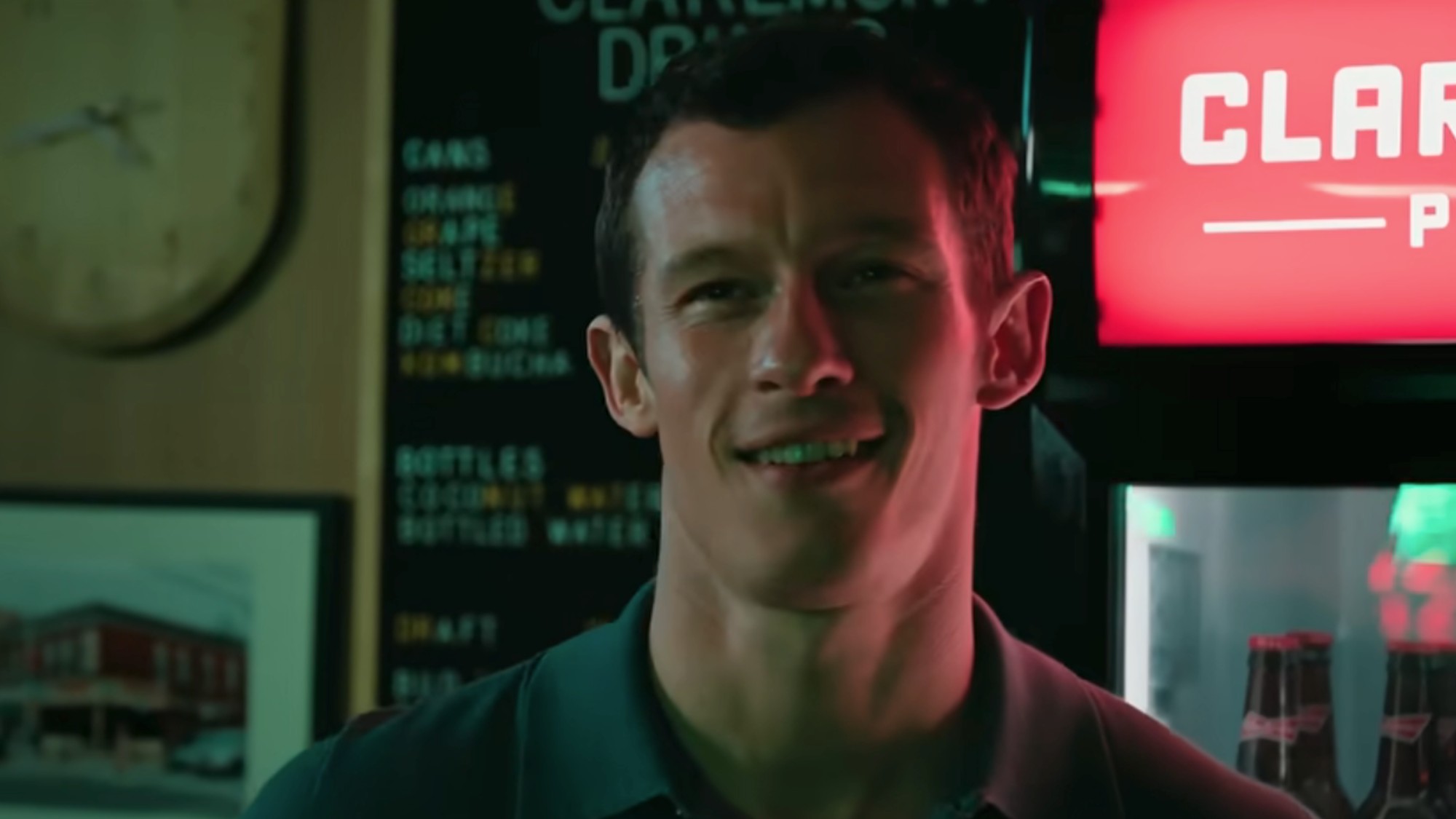 Callum Turner smiling with a soda cooler behind him in One Night Only