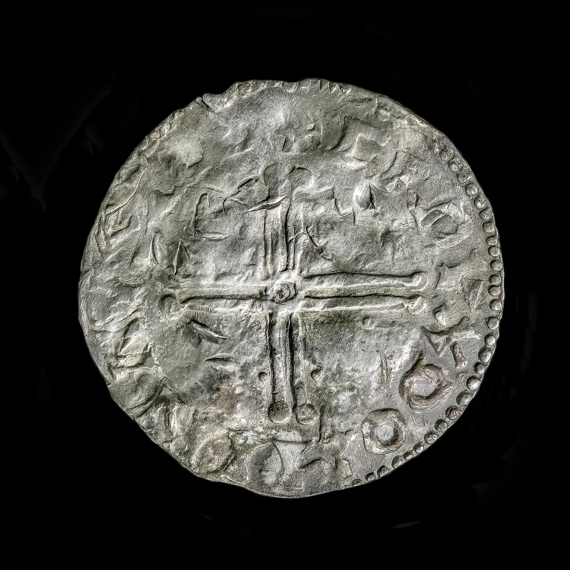 A close up of a silver coin showing a cross