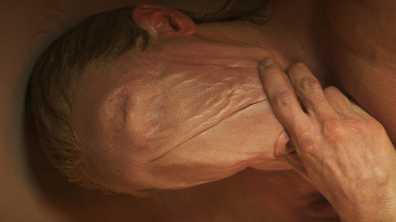 Tom Rhys Harries as Matt Hagen with his skin obscuring his face in the bathtub in Clayface