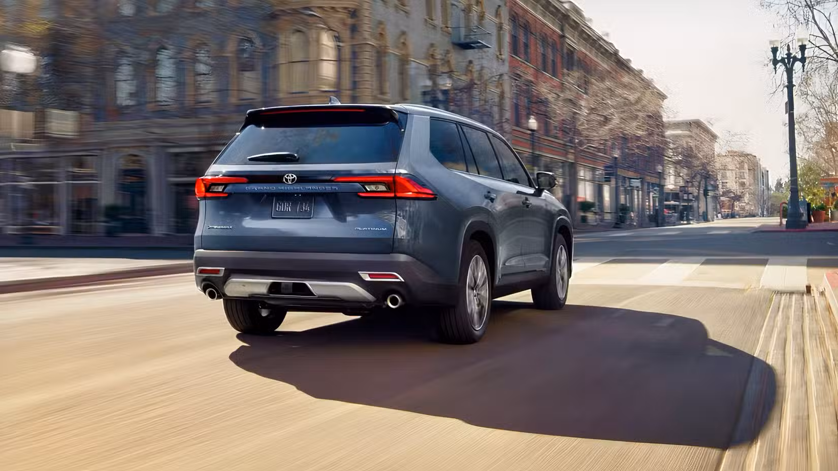 Rear 3/4 action shot of 2026 Toyota Grand Highlander Hybrid driving on road