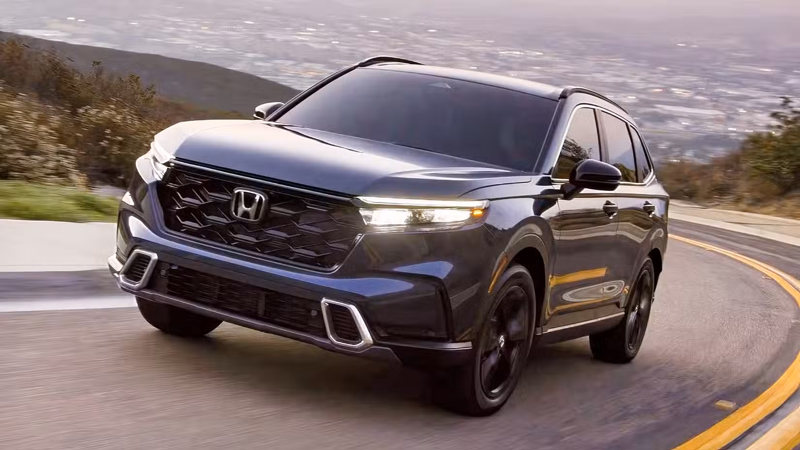 Front 3/4 action shot of 2026 Honda CR-V Sport Touring Hybrid driving on road