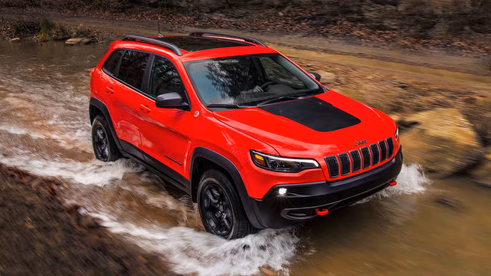 Action shot of 2022 Jeep Cherokee Trailhawk driving through stream