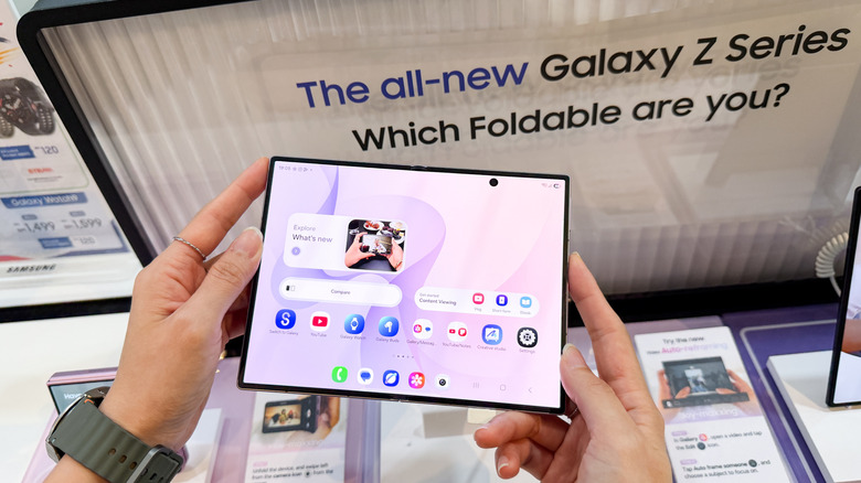 A Galaxy Z Fold8 in a person's hands at an event with promo materials around.