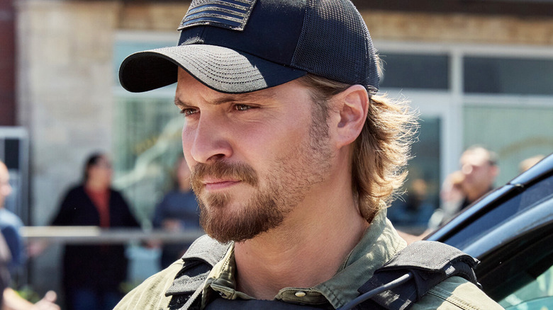 Luke Grimes' Kayce Dutton is seen standing outside in his tactical gear in Marshals