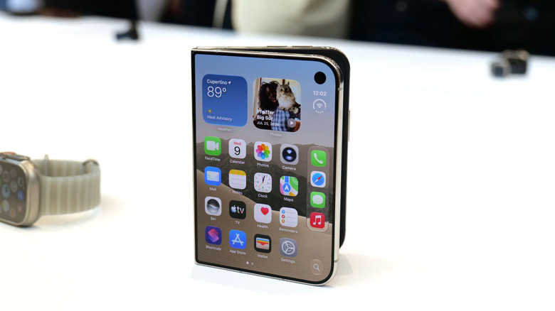 Apple's folding iPhone Duo phone is shown on a white table next to an Apple Watch