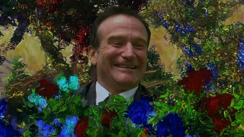 Robin Williams as Dr. Chris Nielsen smiling while sitting in a painting in What Dreams May Come