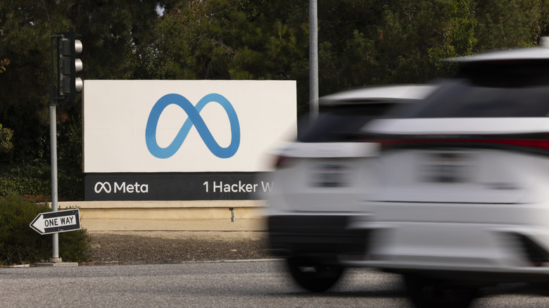 Photo of two blurred white vehicles driving past the sign for Meta's offices.