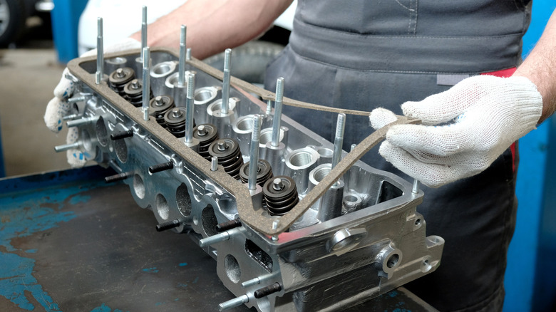 An open engine head with a new head gasket being applied