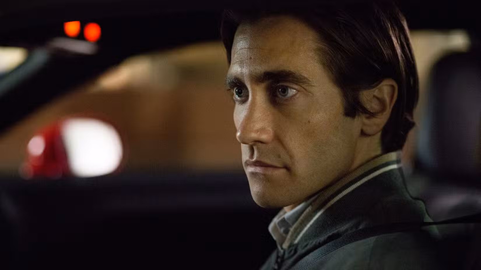 Jake Gyllenhaal sitting in a car as Louis Bloom in Nightcrawler
